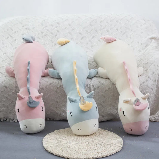 3 peluches geantes de licorne sur un lit