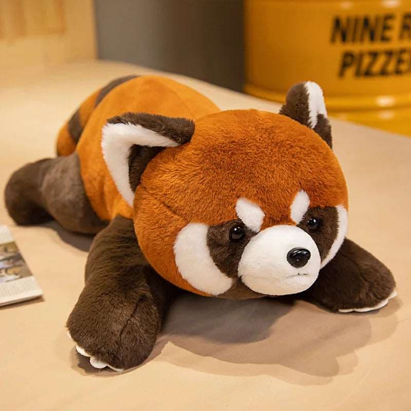 peluche panda roux allongée sur un lit